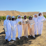 Group of guests in beekeeping suites smiling in the Paso Robles hillside at CASS Winery